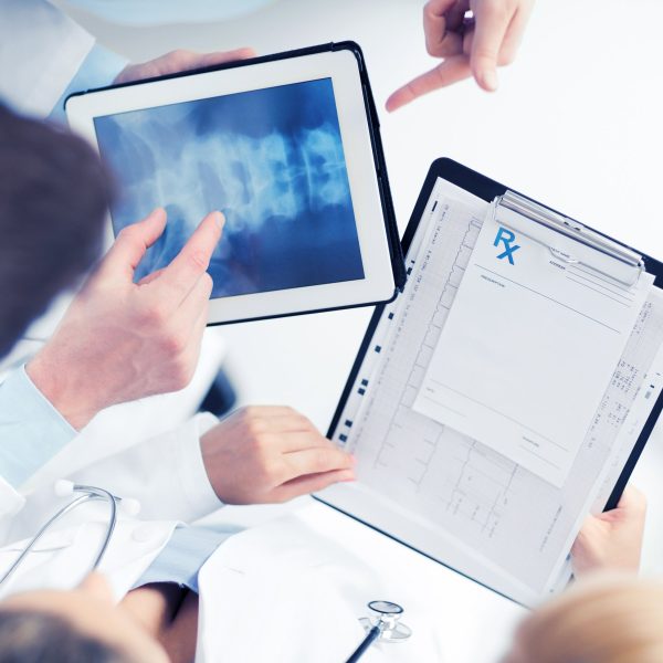 healthcare, hospital and medical concept - group of doctors looking at x-ray on tablet pc